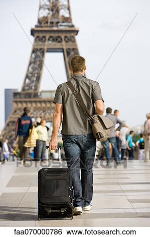 Stock Photograph - Male tourist walking with luggage, Eiffel Tower, Paris, France. Fotosearch