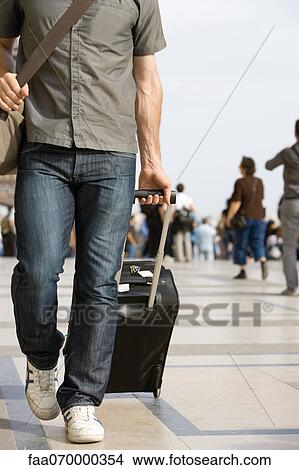 Male traveler walking with luggage, cropped View Large Photo Image Picture - Male traveler walking with luggage, cropped. Fotosearch