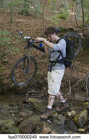Man carrying mountain bike across stream View Large Photo Image Stock Photo - Man carrying mountain bike across stream. Fotosearch