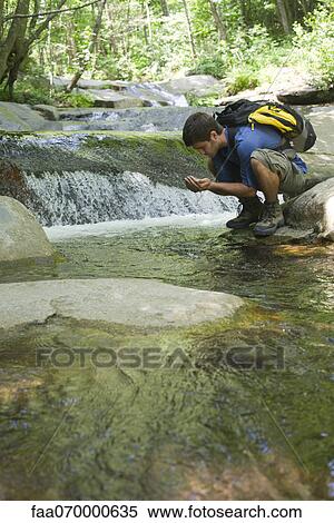 Man crouching by stream, catching water in cupped hands View Large Photo Image Stock Photography - Man crouching by stream, catching water in cupped hands. Fotosearch