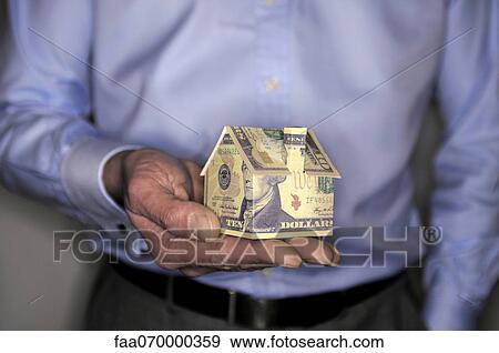 Man holding model house folded with dollar bill, mid section View Large Photo Image Stock Photo - Man holding model house folded with dollar bill, mid section. Fotosearch