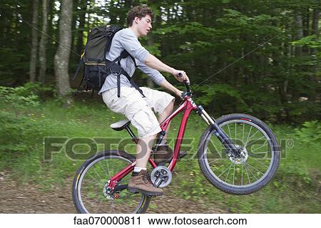 Man performing wheelie on mountain bike View Large Photo Image Stock Image - Man performing wheelie on mountain bike. Fotosearch