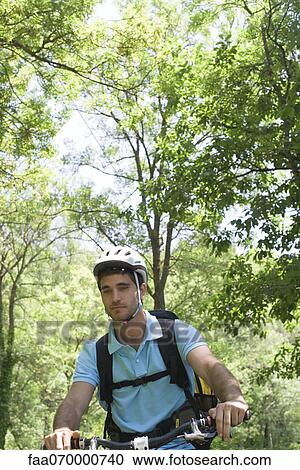 Stock Image - Man riding bicycle in woods. Fotosearch