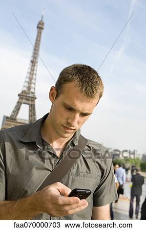 Man text messaging with cell phone, Eiffel Tower in background, Paris, France View Large Photo Image Stock Image - Man text messaging with cell phone, Eiffel Tower in background, Paris, France. Fotosearch