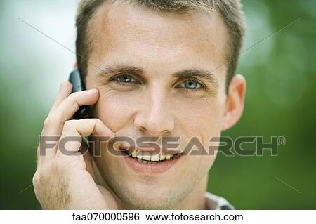 Stock Photograph - Man using cell phone outdoors, portrait. Fotosearch