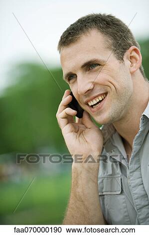 Stock Image - Man using cell phone outdoors. Fotosearch