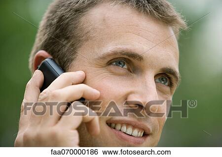 Man using cell phone outdoors View Large Photo Image Stock Photograph - Man using cell phone outdoors. Fotosearch