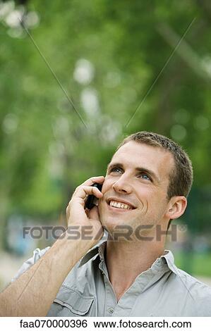 Man using cell phone outdoors View Large Photo Image Stock Photograph - Man using cell phone outdoors. Fotosearch