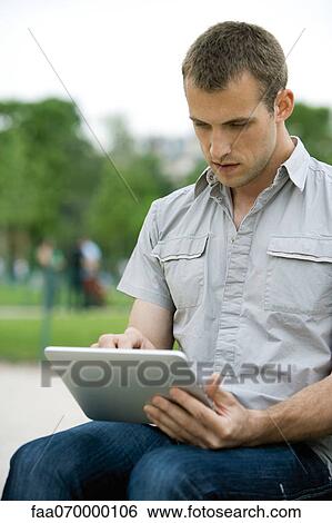Stock Photograph - Man using digital tablet outdoors. Fotosearch
