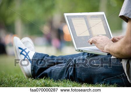 Stock Photo - Man using laptop computer outdoors. Fotosearch