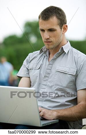 Stock Photo - Man using laptop computer outdoors. Fotosearch