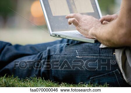 Stock Photograph - Man using laptop computer outdoors. Fotosearch