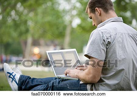 Stock Photograph - Man using laptop computer outdoors. Fotosearch
