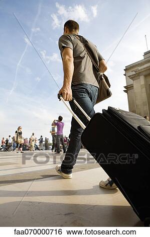 Man walking with rolling luggage View Large Photo Image Stock Photograph - Man walking with rolling luggage. Fotosearch