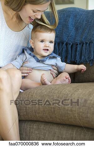Stock Photograph - Mother and infant sitting together on sofa. Fotosearch