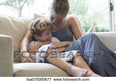 Mother and young son cuddling on sofa View Large Photo Image Stock Photo - Mother and young son cuddling on sofa. Fotosearch