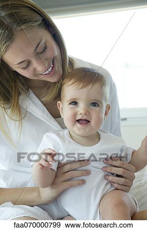 Stock Photo - Mother holding happy baby on lap, portrait. Fotosearch