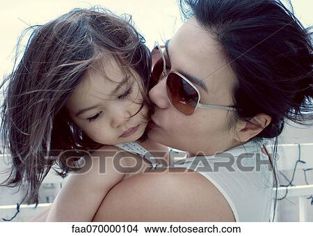 Picture - Mother kissing little girl's cheek. Fotosearch