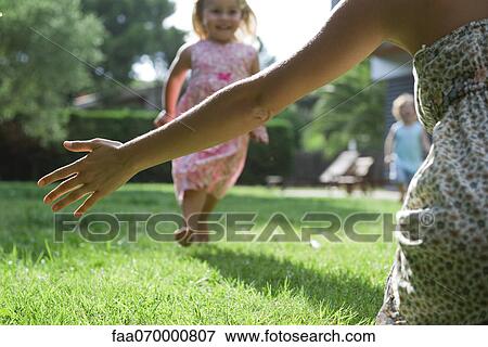 Mother waiting with arms out as young daughter approaches, cropped View Large Photo Image Stock Photo - Mother waiting with arms out as young daughter approaches, cropped. Fotosearch