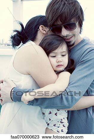 Stock Image - Parents and young daughter embracing. Fotosearch
