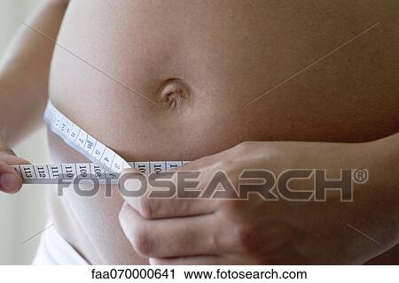 Pregnant woman measuring her belly with measuring tape, cropped View Large Photo Image Stock Image - Pregnant woman measuring her belly with measuring tape, cropped. Fotosearch