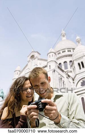 Stock Image - Sightseeing couple looking at digital camera, Sacre Coeur, Montmartre, Paris, France. Fotosearch