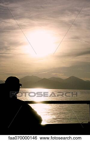 Silhouette of person looking at sunset, rear view View Large Photo Image Stock Photograph - Silhouette of person looking at sunset, rear view. Fotosearch