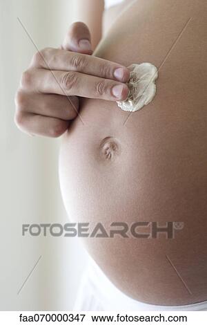 Woman applying moisturizer to pregnant belly, cropped View Large Photo Image Stock Photo - Woman applying moisturizer to pregnant belly, cropped. Fotosearch