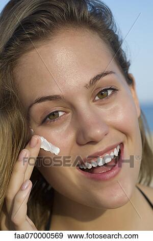 Stock Photo - Woman applying sunscreen, portrait. Fotosearch