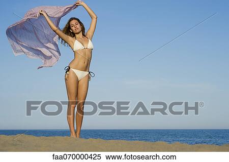 Stock Photography - Woman at the beach, holding scarf out in breeze. Fotosearch