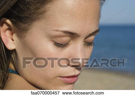 Stock Photo - Woman at the beach with eyes closed, portrait. Fotosearch