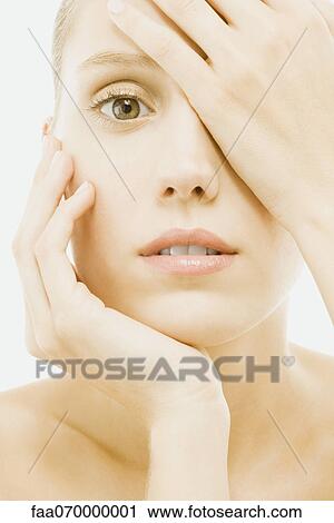 Woman covering eye with one hand, other hand under chin, close-up View Large Photo Image Stock Image - Woman covering eye with one hand, other hand under chin, close-up. Fotosearch