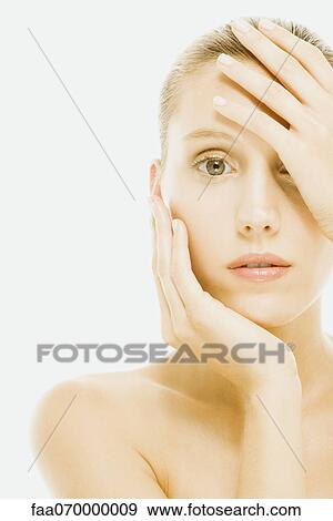 Stock Photo - Woman covering eye with one hand, other hand under chin. Fotosearch
