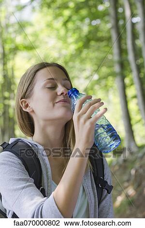 Woman drinking bottled water in woods View Large Photo Image Stock Image - Woman drinking bottled water in woods. Fotosearch