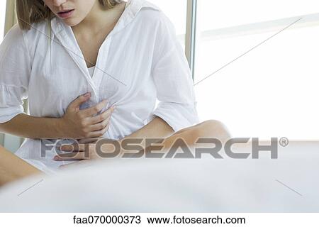 Stock Image - Woman experiencing abdominal pain, cropped. Fotosearch