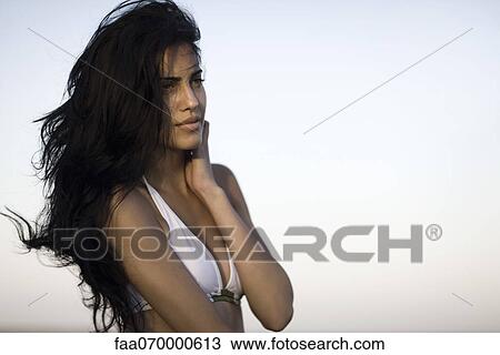 Woman in bikini looking away while long black hair blows in wind, waist up View Large Photo Image Stock Image - Woman in bikini looking away while long black hair blows in wind, waist up. Fotosearch