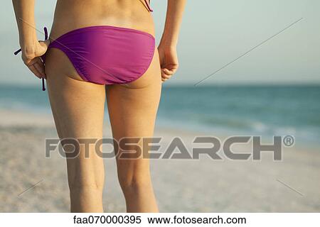 Stock Photography - Woman in bikini on beach, rear view. Fotosearch