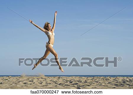 Woman jumping in midair at the beach View Large Photo Image Stock Photo - Woman jumping in midair at the beach. Fotosearch