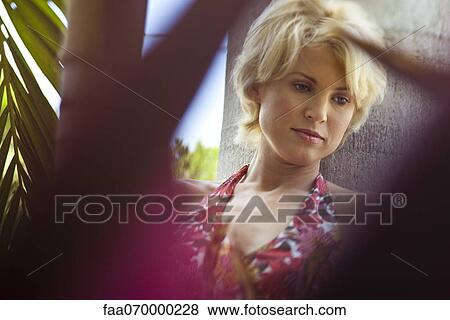 Stock Photo - Woman leaning against tree trunk. Fotosearch
