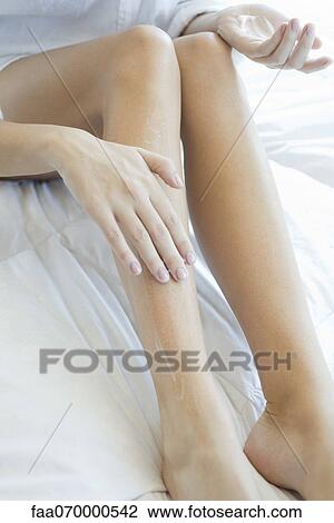 Stock Image - Woman moisturizing legs, cropped. Fotosearch