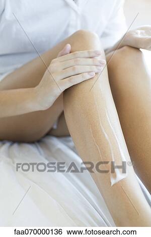 Stock Photograph - Woman moisturizing legs, cropped. Fotosearch