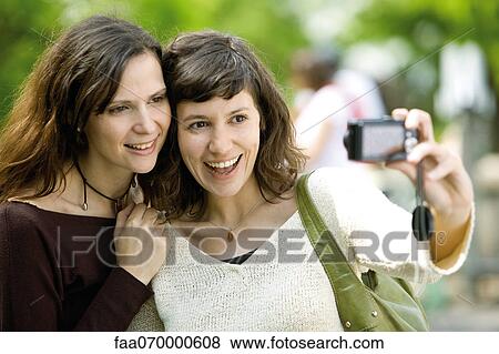Woman photographing herself with friend View Large Photo Image Stock Photo - Woman photographing herself with friend. Fotosearch
