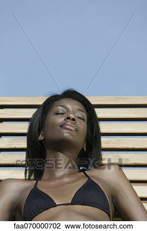 Woman reclining on deckchair, sunbathing View Large Photo Image Stock Image - Woman reclining on deckchair, sunbathing. Fotosearch