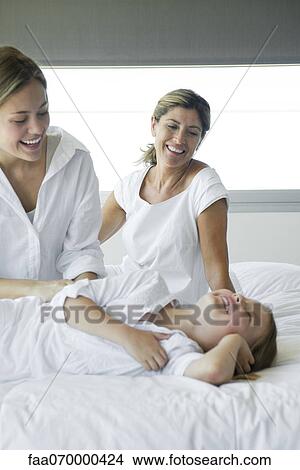 Woman relaxing on bed with daughter and granddaughter View Large Photo Image Picture - Woman relaxing on bed with daughter and granddaughter. Fotosearch