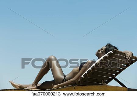 Woman relaxing on deckchair in sun View Large Photo Image Stock Image - Woman relaxing on deckchair in sun. Fotosearch