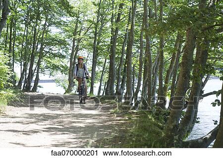 Woman riding bicycle in woods View Large Photo Image Stock Image - Woman riding bicycle in woods. Fotosearch