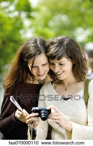 Stock Image - Woman showing digital camera to friend. Fotosearch