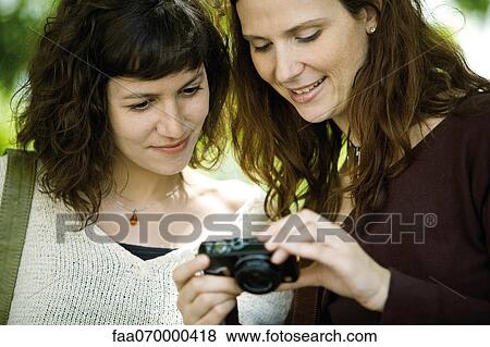 Woman showing digital camera to friend View Large Photo Image Stock Photo - Woman showing digital camera to friend. Fotosearch