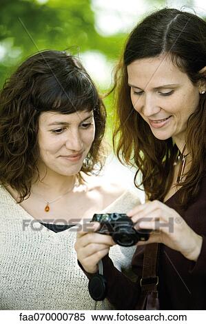 Woman showing digital camera to friend View Large Photo Image Stock Photography - Woman showing digital camera to friend. Fotosearch