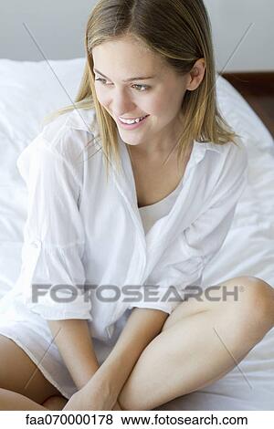 Woman sitting cross-legged on bed, smiling View Large Photo Image Stock Photo - Woman sitting cross-legged on bed, smiling. Fotosearch